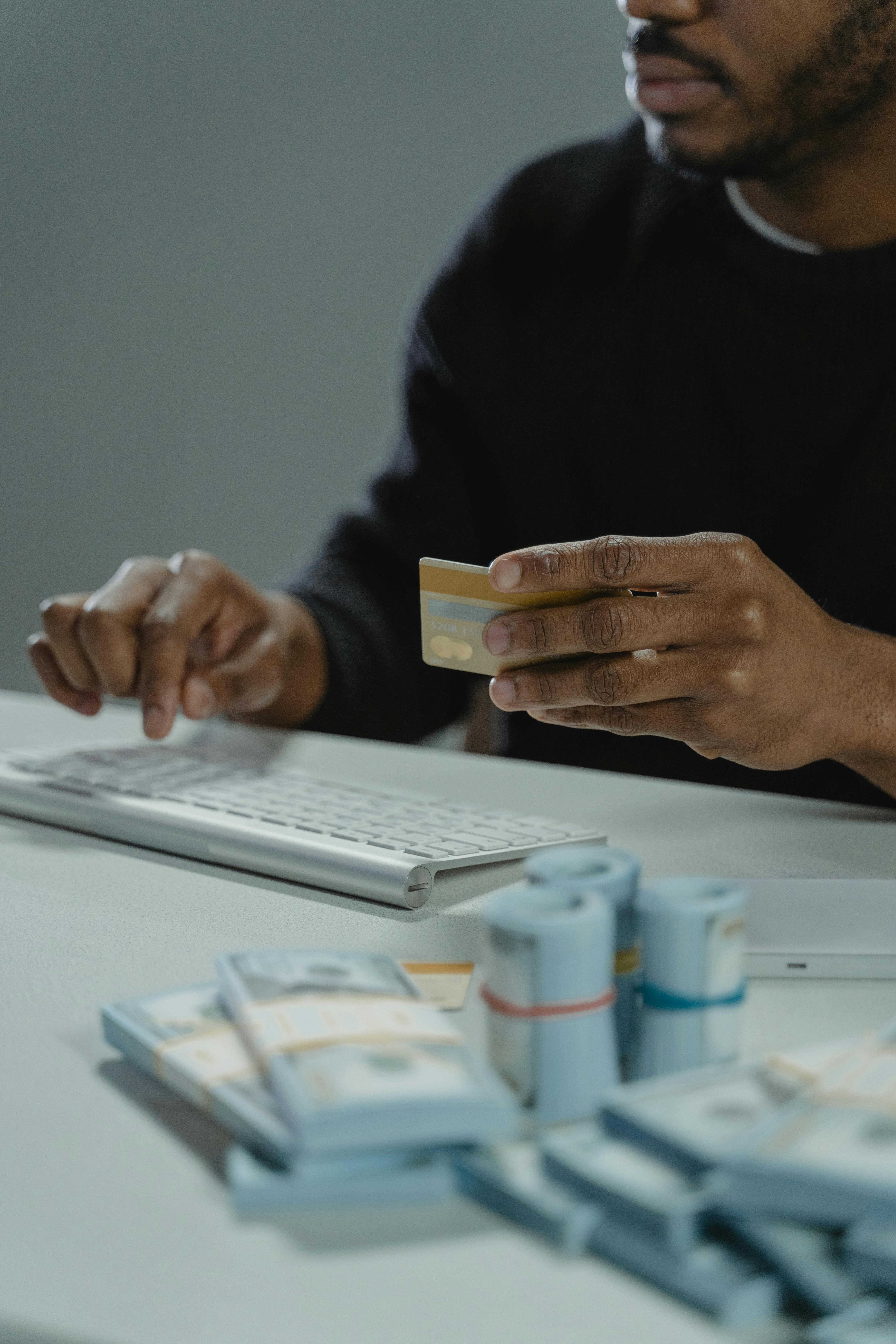 Person at keyboard holding a credit card — representing online payment fraud
